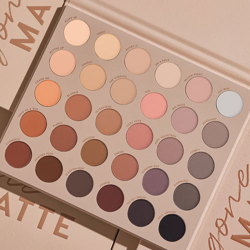Shadow palette opens to reveal 30 all‑matte neutral shades - ivory, peach, taupe, mauve, brown, gray, and black - arranged in a 6x5 grid inside a beige case on a nude backdrop; ColourPop Gone Matte shadow palette for everyday eye looks.