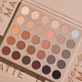 Shadow palette opens to reveal 30 all‑matte neutral shades - ivory, peach, taupe, mauve, brown, gray, and black - arranged in a 6x5 grid inside a beige case on a nude backdrop; ColourPop Gone Matte shadow palette for everyday eye looks.