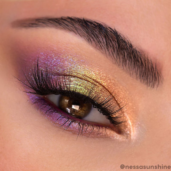 La Mesa ColourPop Super Shock Shadow glows across a partially closed eye, shifting gold, lime, and lavender as it catches light; blended on lid and lower lash line beneath long lashes, highlighting the metallic, duochrome payoff.