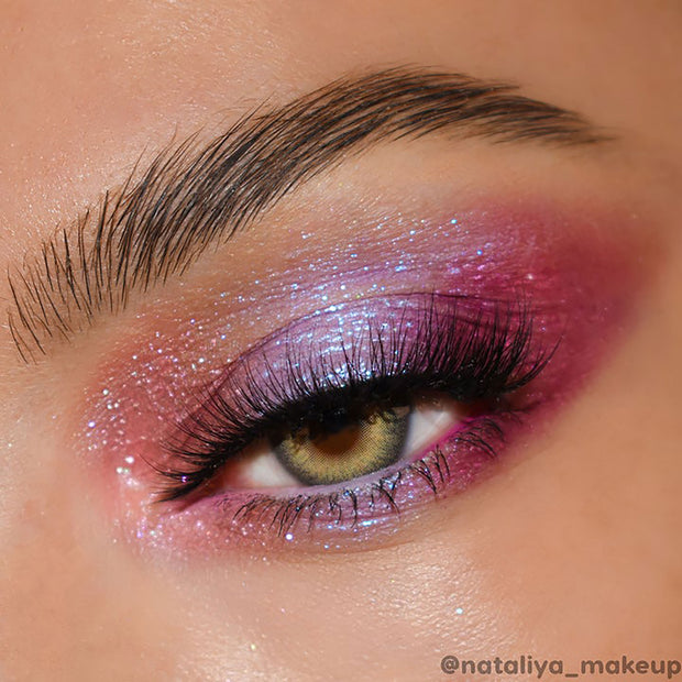 Shimmery rose-lilac eyeshadow sparkles across the eyelid, blended from pink to plum with blue microglitter and long lashes in focus; ColourPop Super Shock Shadow Pug Life shade shown in a close-up beauty look.