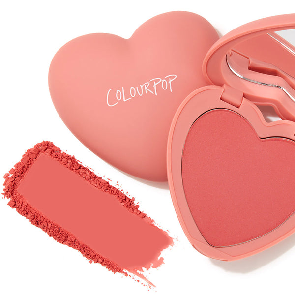 Let’s Dance ColourPop Pressed Powder Blush showcases an open heart-shaped coral-pink compact with mirror, revealing the pressed pan as a matching crushed swatch sits beside it on a white background, ColourPop logo visible on the lid.