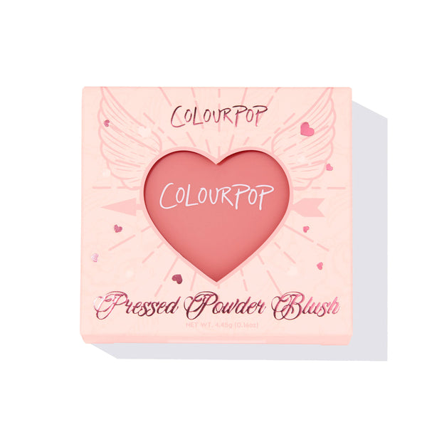 ColourPop Pressed Powder Blush in Let’s Dance displayed through a heart window on a pastel pink box with wing and heart graphics; warm pink blush pan, 4.45 g compact, front-facing on a white background.
