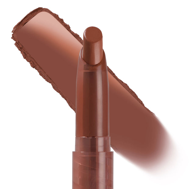 ColourPop Lippie Stix In the Nude standing upright with a smooth, warm brown nude swatch behind it; slim twist-up bullet in a translucent brown tube ready for precise lip application.