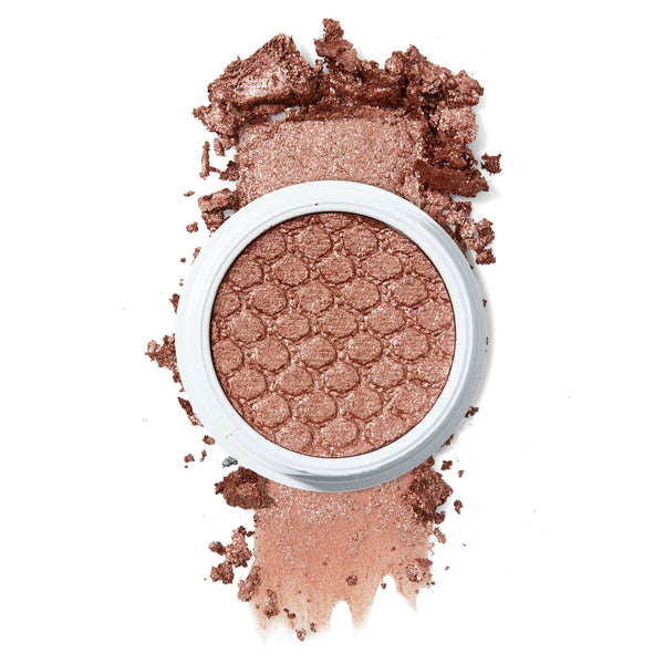 ColourPop Sequin Super Shock Shadow, a shimmering rose-gold eyeshadow, rests in a white round pot with a honeycomb imprint, shown partially crushed and swatched to display its metallic glitter payoff on a clean white background.