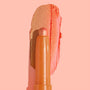 ColourPop Shadow Stix Friday Feels glides a metallic peach-coral swipe across a blush-pink background, showcasing the creamy twist-up eyeshadow crayon and its shimmery finish.