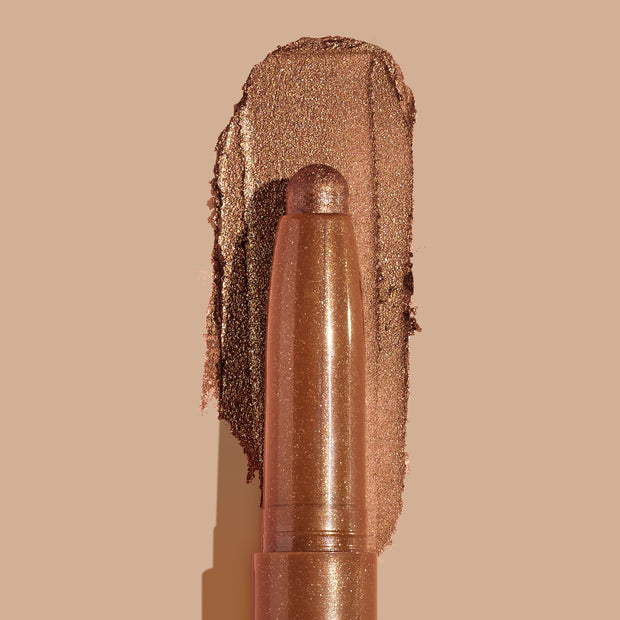 Quokka ColourPop Shadow Stix glides a warm copper-bronze metallic swatch, the creamy eyeshadow stick with a rounded tip centered over its shimmery smear on a nude background.