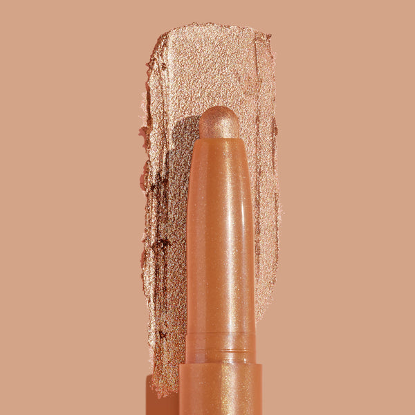 ColourPop Shadow Stix Walk of Fame eyeshadow stick glides a metallic champagne‑gold swatch, showcasing creamy shimmer payoff and a rounded tip, on a warm nude background in a clean close-up product shot.