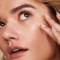 ColourPop Pretty Fresh Creamy Concealer in Light 60 N dotted under the eye and blended with a fingertip, close-up of a model's dewy skin showing smooth, natural coverage.