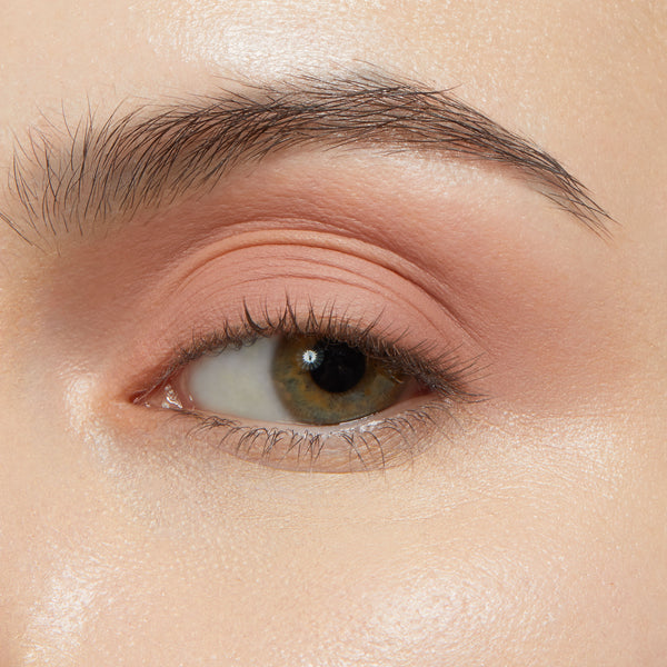 Eyelid wearing ColourPop Shadow Stix in Bare With Me, a soft peach nude eyeshadow stick, blended smoothly across the lid for a matte, crease-free finish, shown in close-up with natural lashes under studio lighting.