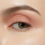 Eyelid wearing ColourPop Shadow Stix in Bare With Me, a soft peach nude eyeshadow stick, blended smoothly across the lid for a matte, crease-free finish, shown in close-up with natural lashes under studio lighting.