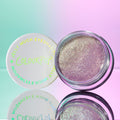 Open jar of ColourPop Jelly Much Shadow in Big Ego showcasing a shimmering lavender-silver gel eyeshadow, set beside its white lid with iridescent logo on a pastel mint-and-pink gradient surface with a mirrored reflection.