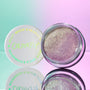 Open jar of ColourPop Jelly Much Shadow in Big Ego showcasing a shimmering lavender-silver gel eyeshadow, set beside its white lid with iridescent logo on a pastel mint-and-pink gradient surface with a mirrored reflection.