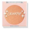 Boombox compact showcasing a closed ColourPop Pressed Powder Highlighter in shade Boombox, a warm peach‑gold shimmer pan set in a pale pink square case with a clear lid, white star accents, and the ColourPop logo.