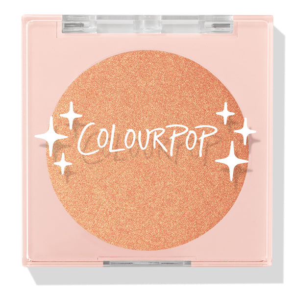 Boombox compact showcasing a closed ColourPop Pressed Powder Highlighter in shade Boombox, a warm peach‑gold shimmer pan set in a pale pink square case with a clear lid, white star accents, and the ColourPop logo.