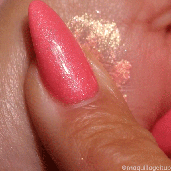 ColourPop Jelly Much Shadow Buzzy swatch - sparkling peach-gold gel eyeshadow with pink-coral shimmer - being swiped on skin by a coral-painted fingertip, showcasing a high-shine metallic finish and bold, long-wear payoff.