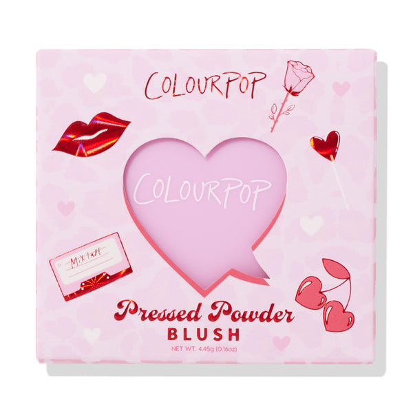 ColourPop Pressed Powder Blush Cupid’s Bow displayed in a pink Valentine-themed box, heart-shaped window revealing the blush, with red lip, rose, heart lollipop, cherries, and mixtape illustrations; square 4.45 g compact on a white backdrop.