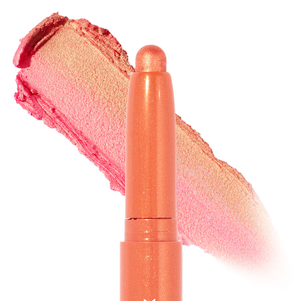 ColourPop Shadow Stix in Friday Feels stands upright with its cap off, showing a shimmery peach‑coral tip and a bold swatch behind that shifts pink to golden champagne, highlighting the creamy eyeshadow stick's metallic finish on a clean white background.