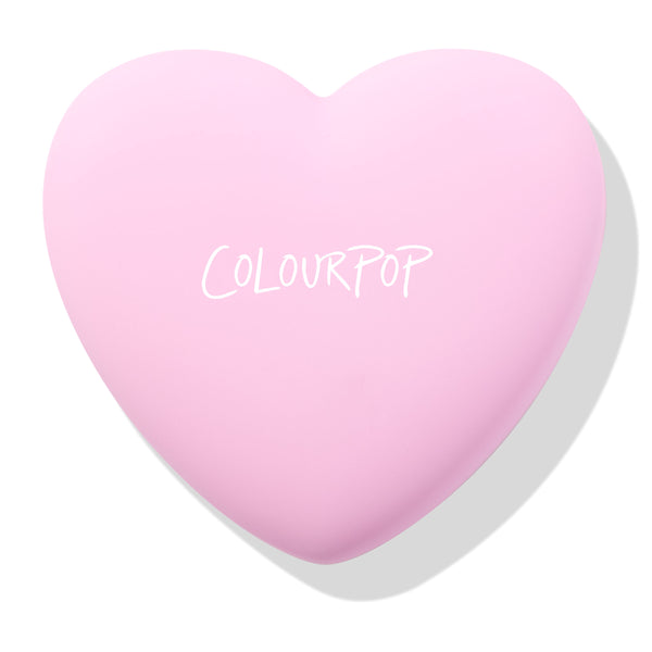 Hot 2 Touch ColourPop Pressed Powder Blush compact, a pastel pink heart-shaped case with COLOURPOP logo, shown closed and resting at an angle on a white background with a soft shadow.