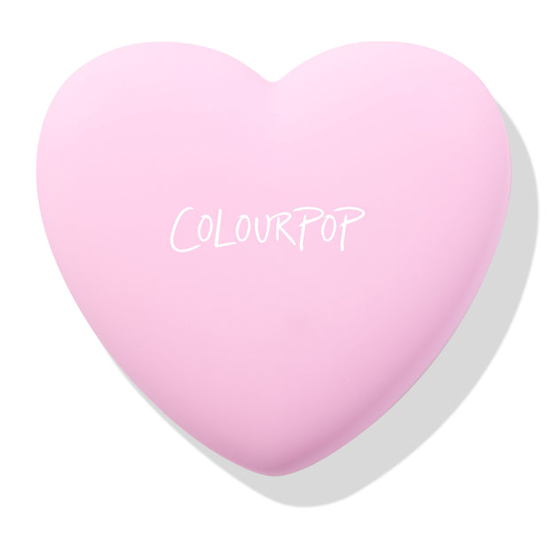 Hot 2 Touch ColourPop Pressed Powder Blush compact, a pastel pink heart-shaped case with COLOURPOP logo, shown closed and resting at an angle on a white background with a soft shadow.
