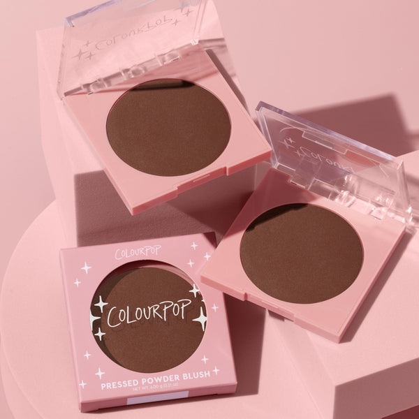 Latte Run ColourPop Pressed Powder Blush displayed in two open pink compacts and one boxed unit, revealing a deep latte-brown matte pan; styled on pastel pink blocks with clear lids and soft shadows.