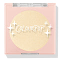 Minted pressed powder highlighter compact showcasing a shimmering champagne-gold pan, closed in a blush-pink square case with clear lid and ColourPop logo and star accents on a white background; ColourPop Pressed Powder Highlighter.