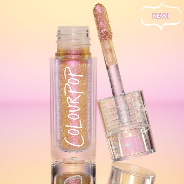 Bliss ColourPop Chrome Liquid Shadow opened, the shimmery multichrome wand resting on a clear cap with star accents, showing pink‑to‑gold‑lilac shift in a clear tube labeled ColourPop, set on a reflective peach‑to‑pink gradient backdrop with a NEW badge.