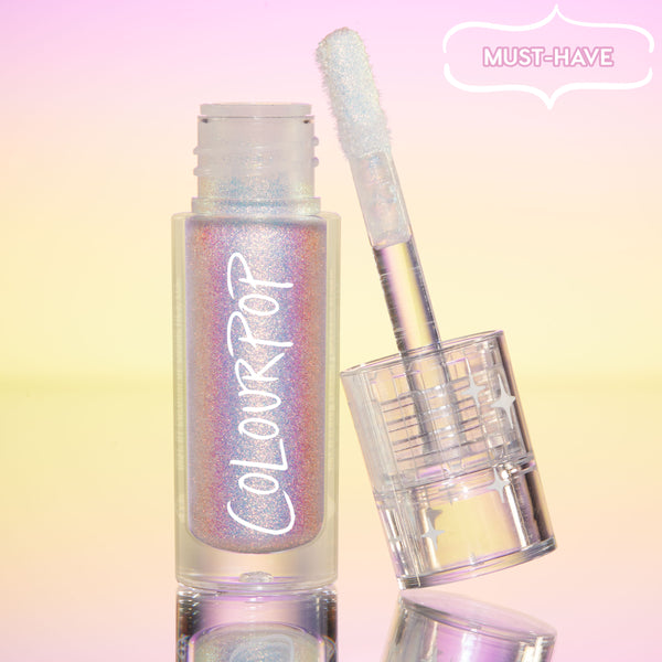 ColourPop Chrome Liquid Shadow in Glaze stands open, doe-foot applicator leaning on the iridescent tube, multichrome shimmer shifting pink, lilac, and blue, set on a pastel pink-to-yellow gradient with a “Must-Have” badge and mirrored surface.