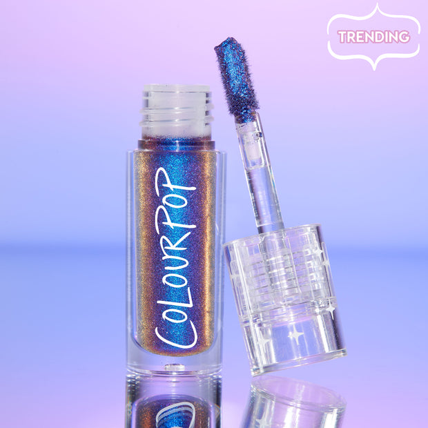 Morpho ColourPop Chrome Liquid Shadow stands open with a doe-foot applicator showing a blue-to-purple-to-bronze multichrome shimmer in a clear tube with ColourPop logo, set on a lilac gradient mirrored surface with a “Trending” tag.