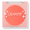 Papaya pressed powder blush sits as a vivid coral pan in a closed translucent pink square compact, featuring the COLOURPOP logo and white star accents; ColourPop Pressed Powder Blush for a warm, bright cheek flush.