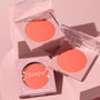 Papaya, a coral-peach ColourPop Pressed Powder Blush, displayed in two open pans and one boxed compact on soft pink blocks, clear lids with star accents catching light to show the matte finish for fresh, everyday cheeks.