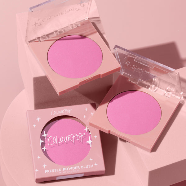 Pitaya pressed powder blush compact showing a vibrant cool-toned pink pan, arranged with two matching compacts on a monochrome pink backdrop, clear lids and star accents visible, featuring ColourPop Pressed Powder Blush branding and 4.0 g net weight.