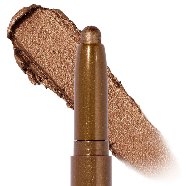 Quokka Shadow Stix glides on in a shimmery warm bronze, shown as a twist-up cream eyeshadow crayon with a metallic swatch backdrop, highlighting the smooth, blendable payoff of the ColourPop Shadow Stix.
