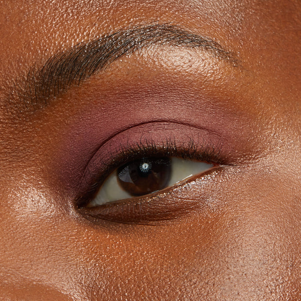 Close-up eyelid wearing matte plum-mauve shadow, ColourPop Shadow Stix in Plum Tart blended across the lid with a soft, crease-free finish, highlighting rich pigment and smooth texture in studio lighting.