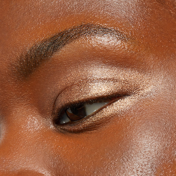 Shimmery champagne-bronze eyeshadow sweeps across a closed eyelid, showcasing the Walk of Fame shade from ColourPop Shadow Stix in a tight close-up beauty swatch under soft light.